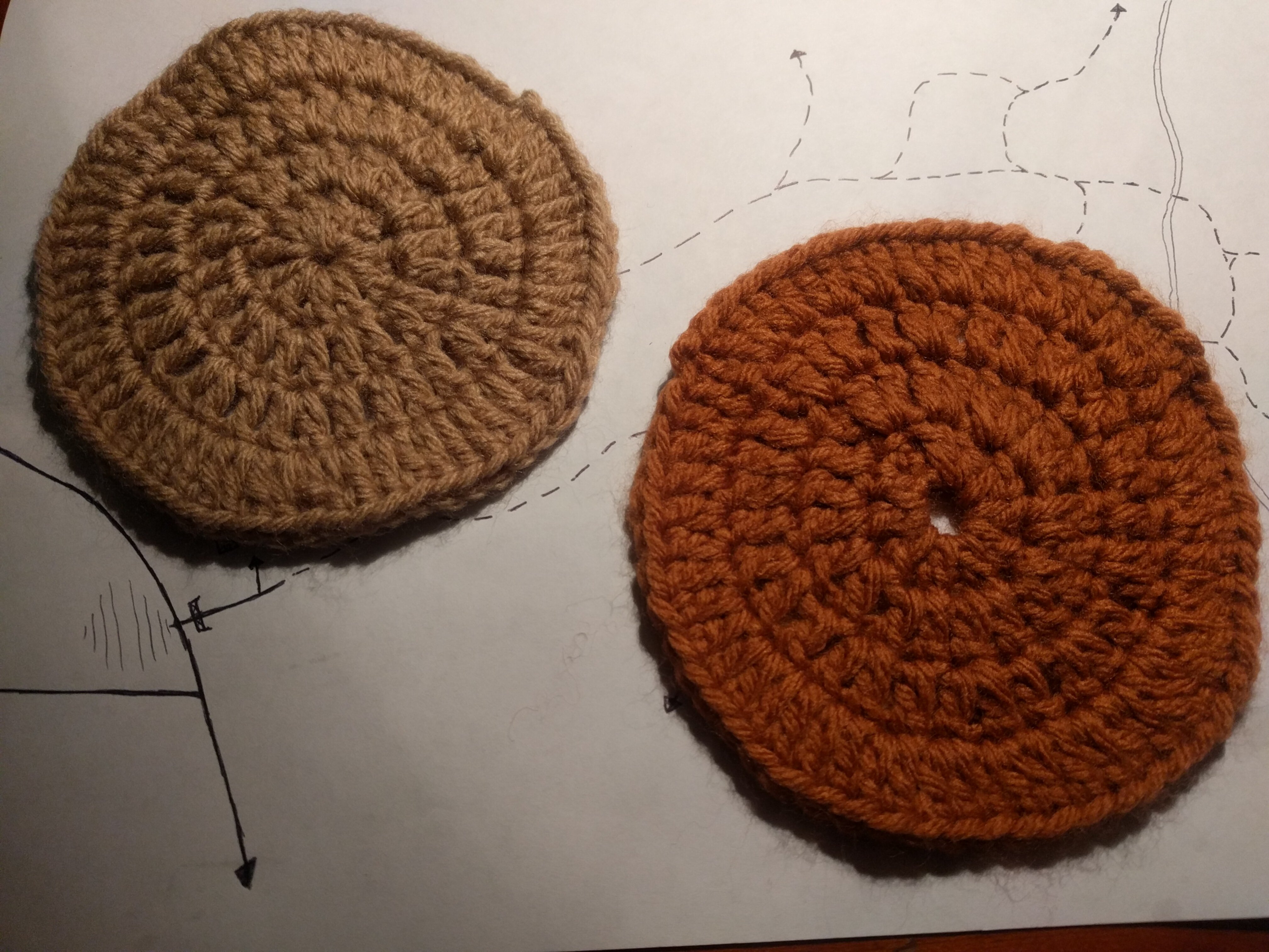 Two crocheted round coasters, one beige and one red-brown