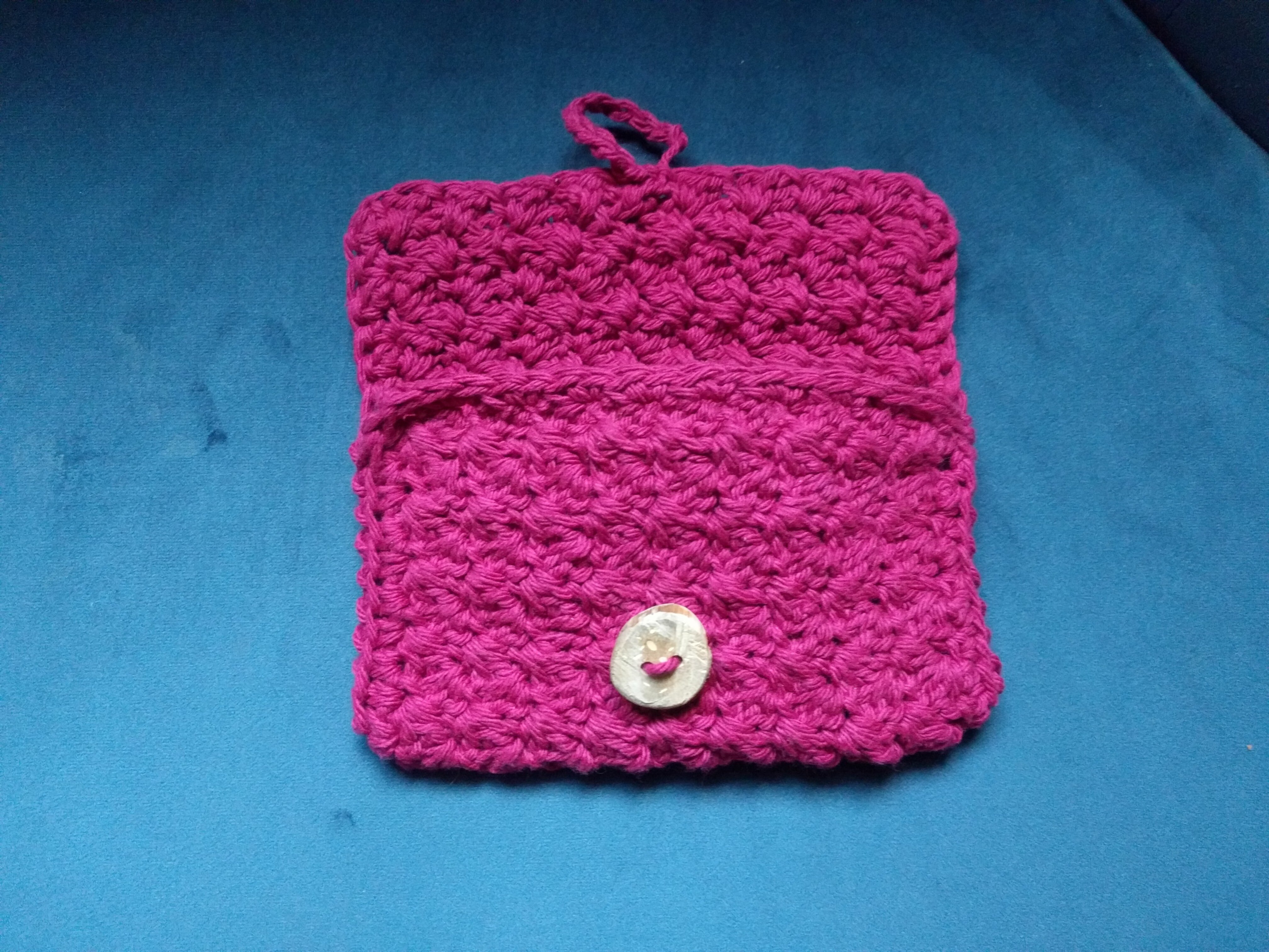 A redish-purple crocheted wallet with its flap opened and unbuttoned