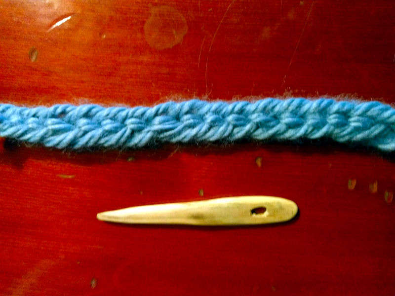 A nålebinding sample in oslo stitch above a wooden needle